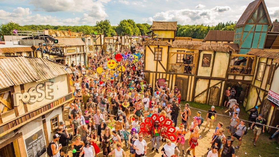 Boomtown Fair festival crowd and immersive stage set near Winchester, England