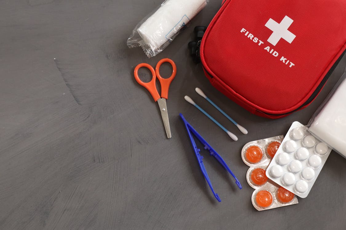 First aid kit with medical supplies on gray background - travel health essentials