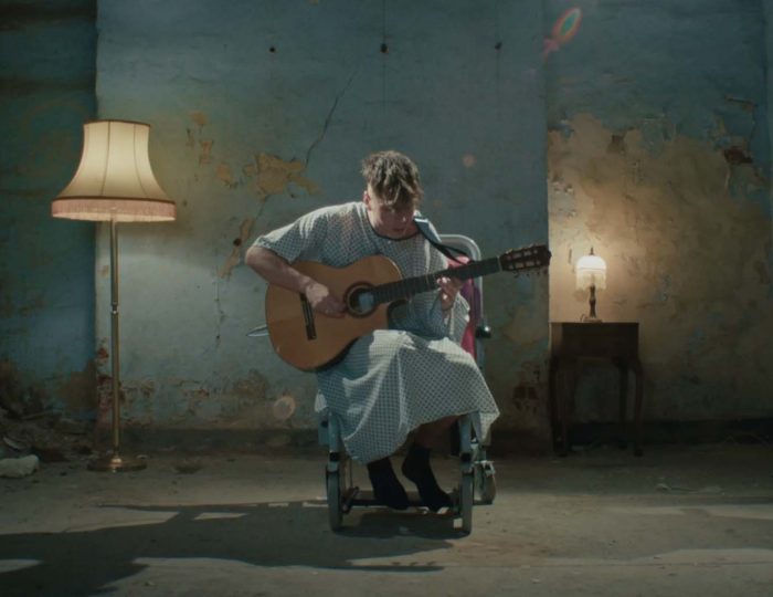 Ren performing live with an acoustic guitar in a warmly lit room