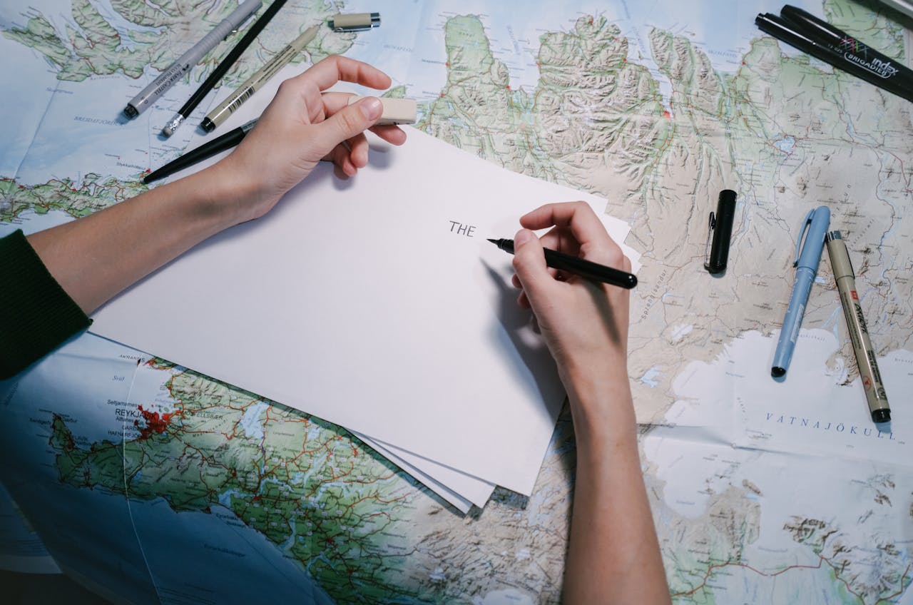 Hands writing notes on a world map while planning a sabbatical